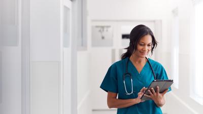 female nurse standing looking at tablet