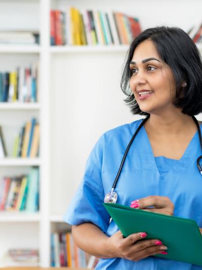 Nurse with clipboard in front of bookshelf