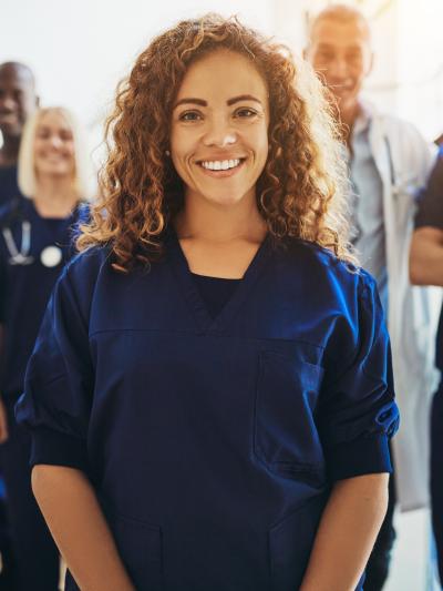 Female nurse standing in front of smiling colleagues