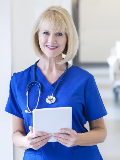 Older nurse standing with tablet