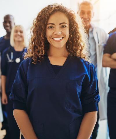 Female nurse standing in front of smiling colleagues