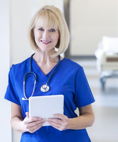 Older nurse standing with tablet
